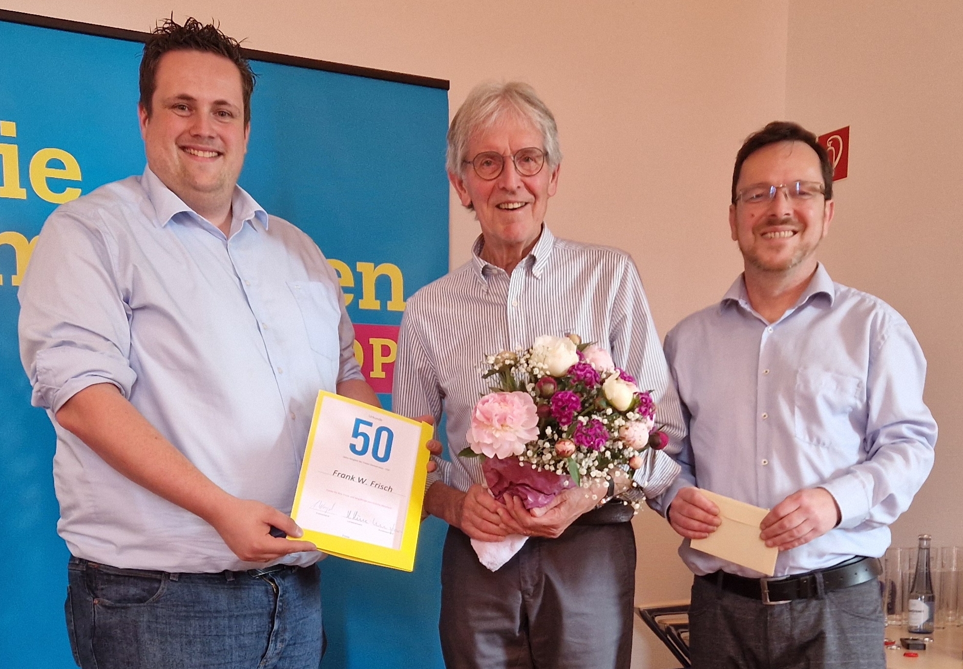 Andreas Weigel, Vorsitzender des FDP Kreisverbandes und Tibor Zachar, Stadtverbandsvorsitzender überreichen Frank W. Frisch die Urkunde und die goldene Theodor Heuss Medaille.